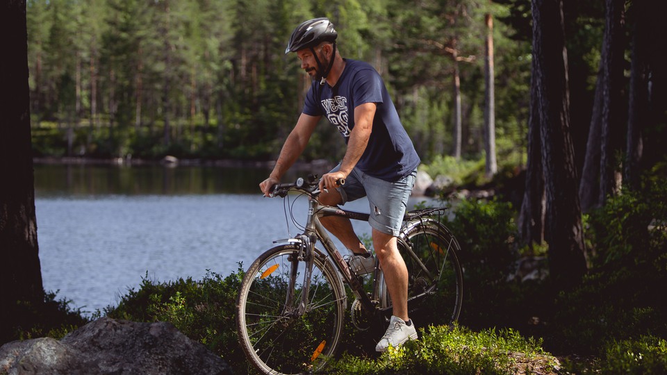 Man som cyklar vid en skogssjö i Ludvika kommun.